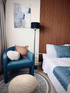 Un dormitorio con una silla azul junto a una cama en Happy House T8, en Thung Si Kan