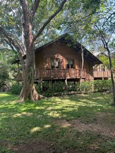 a log cabin with a porch and a tree at The Other Corner Habarana in Habarana