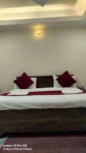 a large bed with red and white pillows on it at New Shanti Hotel in Prayagraj