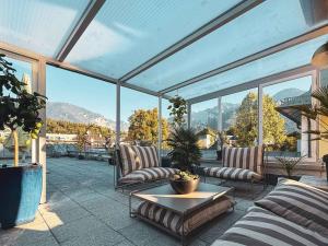 a conservatory with couches and a table and windows at Villa Dora Petit Hôtel in Bad Reichenhall