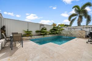 a swimming pool in a backyard with a table and chairs at Poolside Escape Scarborough in Scarborough