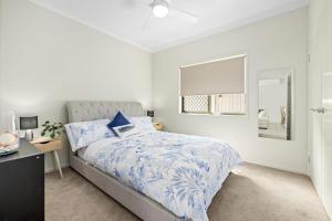 a bedroom with a bed with a blue comforter at Poolside Escape Scarborough in Scarborough +9 photos