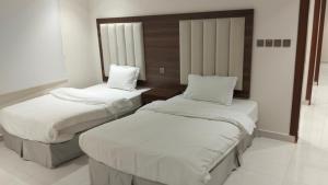 a room with two beds with white sheets at رير بلو دايموند 2 للشقق المخدومة تصنيف اقتصادي in Taif