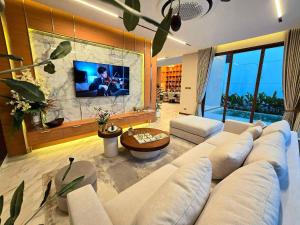a living room with a large couch and a tv at Home atmos prime villa pattaya in Ban Hui Yai Muk