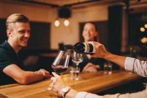 a person pouring a glass of wine at a bar at THOMSN Central Hotel & Appartements in Saalbach-Hinterglemm