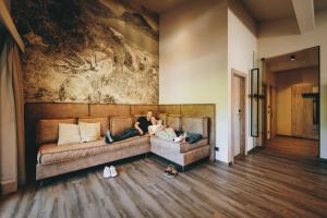 a woman sitting on a couch in a living room at THOMSN Central Hotel & Appartements in Saalbach-Hinterglemm