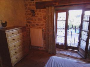 a bedroom with a dresser and a large window at La maison la Borie in Baffie