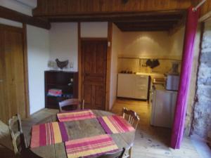 a dining room with a table and a kitchen at La maison la Borie in Baffie