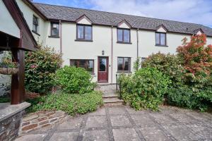 a white house with a red door and some bushes at Host & Stay - Coombe Cottage in Knowstone
