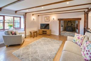 a living room with a couch and a television at Host & Stay - Coombe Cottage in Knowstone