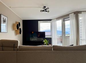 a living room with a couch and a tv and windows at Fjord and Mountain View in Tromsø