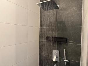 a shower with a black and white tile wall at Zentrale Citywohnung Bayreuth, Loggia, Garage in Bayreuth
