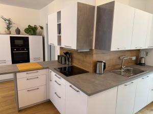 a kitchen with white cabinets and a sink at Zentrale Citywohnung Bayreuth, Loggia, Garage in Bayreuth