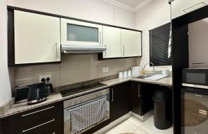 a kitchen with white cabinets and a microwave at uMhlanga Condo - Location, Location, Location in Durban