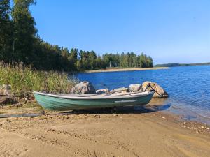 a small boat sitting on the shore of a lake at Homely Loft in Punkaharju