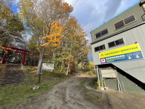 una strada sterrata vicino a un edificio con un cartello di Snow Resort Hermitage a Asahikawa