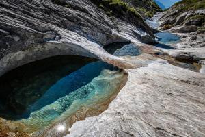a rock cave with a pool of water at Casa Partnun 2-9 in Laax-Murschetg