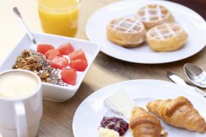 a table with plates of breakfast foods and a cup of coffee at Scandic Berlin Kurfürstendamm in Berlin