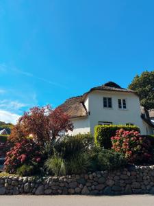 ein weißes Haus mit einem Strohdach und Blumen in der Unterkunft Ferienhaus Pauline in Glücksburg