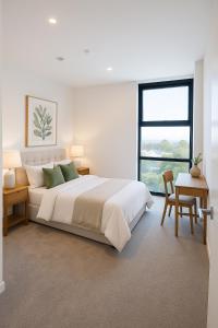 a white bedroom with a large bed and a window at FREE Parking Modern 2 bedrooms Apt for Family or Business in Sydney