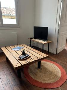 a wooden table in a room with a laptop on a table at Cocon au cœur du centre ville de Bazas in Bazas