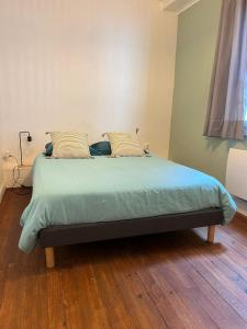 a bed in a room with a wooden floor at Cocon au cœur du centre ville de Bazas in Bazas