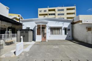a white house with a building in the background at 海徒歩1分アメリカンビレッジまで7分周辺には飲食店多数の北谷エリアSunabeNest in Chatan