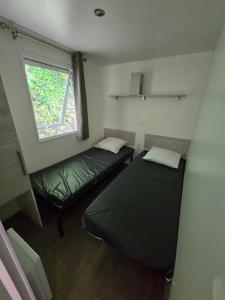 una piccola stanza con due letti e una finestra di MOBIL-HOME 6 Places Saint-George de Didonne a Saint-Georges-de-Didonne