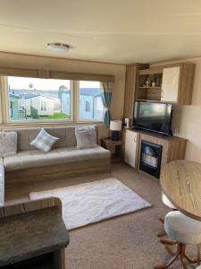 a living room with a couch and a tv and a table at Lapwing Lea 16, Thornwick Bay in Flamborough