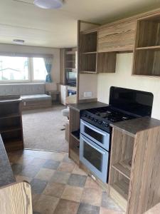 a kitchen with a stove and a living room at Lapwing Lea 16, Thornwick Bay in Flamborough