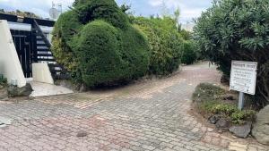 un cartello su un marciapiede di mattoni accanto ad alcuni cespugli di Villa-Port Nature-Village Naturiste-1 chambre a Cap d'Agde Altre 9 foto