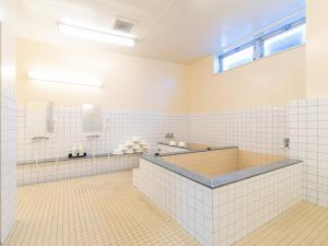 a white tiled bathroom with a tub and a sink at Tabist Hotel Centro Kanoya in Kanoya +43 photos