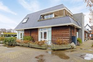 a wooden house with a grey roof at The marine apartment near Amsterdam by Weltevreden Experience in Kortenhoef