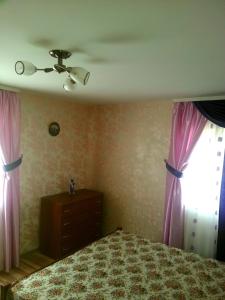 a bedroom with pink curtains and a bed and a window at AgroecoUsadba U Druzey in Gorodnya