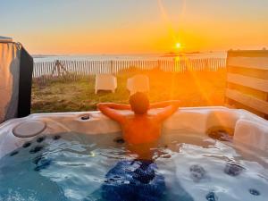 Un uomo in una vasca idromassaggio che guarda il tramonto di Le Spa sur la dune, Santec, Bretagne a Santec