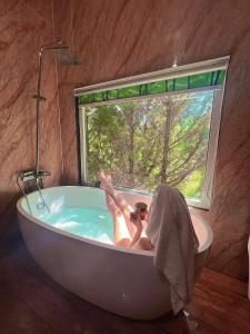 a woman laying in a bath tub with a window at HomeStay Thiên Phúc in Ấp Ðinh An (1)