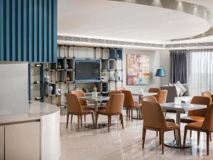 a dining room with tables and chairs and a tv at Novotel Vijayawada Varun in Vijayawāda