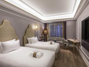 a hotel room with two beds and a desk at Mercure Shanghai Jiuting in Shang-hai
