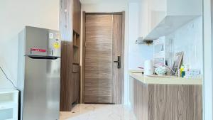 a kitchen with a refrigerator and a wooden door at Artisan Ratchada Condo Bangkok in Bangkok