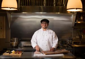 a chef standing in a kitchen holding a piece of bread at Enchante Boutique Hotel in Los Altos