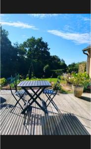 een picknicktafel en een stoel op een houten terras bij Les hortensias in Lannion