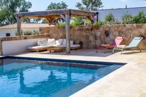 a swimming pool with chairs and a couch next to a stone wall at Villa A Calia di Fiori Mare in Sainte-Lucie de Porto-Vecchio +35 photos