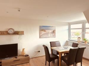 a dining room with a table and chairs and a tv at Ferienwohnung Hotel Preyt in Holtland