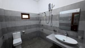 a bathroom with a sink and a toilet and a mirror at Kulassa Homes in Anuradhapura +23 photos