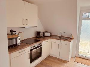 a kitchen with white cabinets and a sink and a microwave at Ferienwohnung Hotel Preyt in Holtland