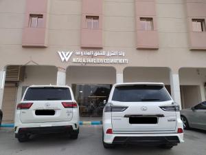two white cars parked in front of a building at وتد الشرق للشقق المخدومة in Khafji