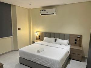 Un dormitorio con una cama grande blanca con aire acondicionado. en وتد الشرق للشقق المخدومة, en Al Khafji