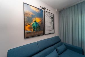 - un salon avec un canapé bleu et deux photos dans l'établissement Bright and Blue 3city Apartment with Balcony in Gdynia by Noclegi Renters, à Gdynia