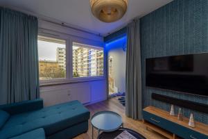 un salon avec un canapé bleu et une grande fenêtre dans l'établissement Bright and Blue 3city Apartment with Balcony in Gdynia by Noclegi Renters, à Gdynia