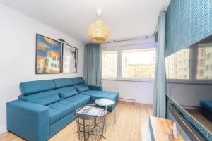 un salon avec un canapé bleu et une fenêtre dans l'établissement Bright and Blue 3city Apartment with Balcony in Gdynia by Noclegi Renters, à Gdynia